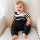 Baby on a cream chair wearing black Aaron textured crochet pants. Digital pattern PDF, sizes Newborn to 2 Years.