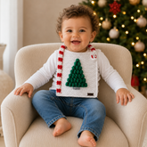 Toddler wearing the Chrissy crochet bib with green Christmas tree and red-and-white striped border. Digital PDF pattern.