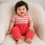 Baby wearing Coral pink crochet leggings with drawstring waist on a cream chair for a newborn-to-2-years digital pattern PDF.