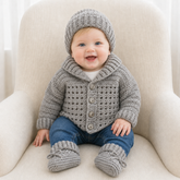 Baby in silver Corbin shawl collar crochet cardigan, hat and booties, blue jeans on a cream chair, 0–2Y digital pattern PDF