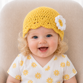 Baby wearing yellow Daisy crochet beanie with white flower and floral shirt on beige chair, Prem–12M digital pattern PDF