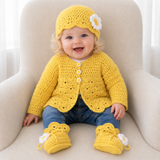 Baby in blue jeans on a cream chair wears a yellow Daisy crochet cardigan, hat and booties. Digital pattern PDF set, NB–12M.