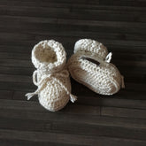 Cream Grayson crochet baby booties on wood, one upright and one lying down. Digital pattern PDF, sizes Preemie to 1 Year.