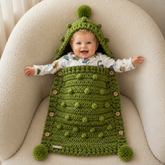 Smiling baby in the Hunter green bobble crochet sleep sack with hood pompoms and wooden buttons for a digital pattern PDF.