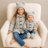 Girl and baby in jeans wear silver Theo crochet cardigans and hats on cream chair; baby wears booties. Digital pattern PDF.