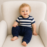 Baby wearing William navy textured crochet trousers and striped shirt on a cream chair for a Preemie–2Y digital pattern PDF.