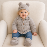 Baby wearing taupe Zac collared crochet cardigan, hat and booties with blue jeans on a cream chair, 0–2Y digital pattern PDF.