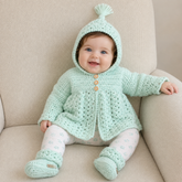 Baby in white floral leggings on a cream chair wears a Zara hooded crochet cardigan and booties. Digital pattern PDF set, 0–3M.