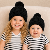 Older girl and baby on a cream chair wear black Aaron crochet beanies. Digital pattern PDF, sizes Preemie to 10 Years.