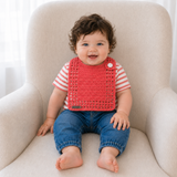 Baby wearing Coral pink adjustable crochet drool bib over a coral-and-white striped shirt for a digital pattern PDF.