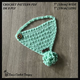 Mint green Fiona crochet bandana bib with crocheted pompom flat lay on wood. Digital pattern PDF details and DK 8 Ply yarn.
