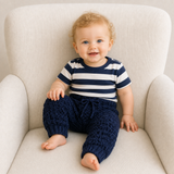 Baby wearing William navy textured crochet trousers and striped shirt on a cream chair for a Preemie–2Y digital pattern PDF.