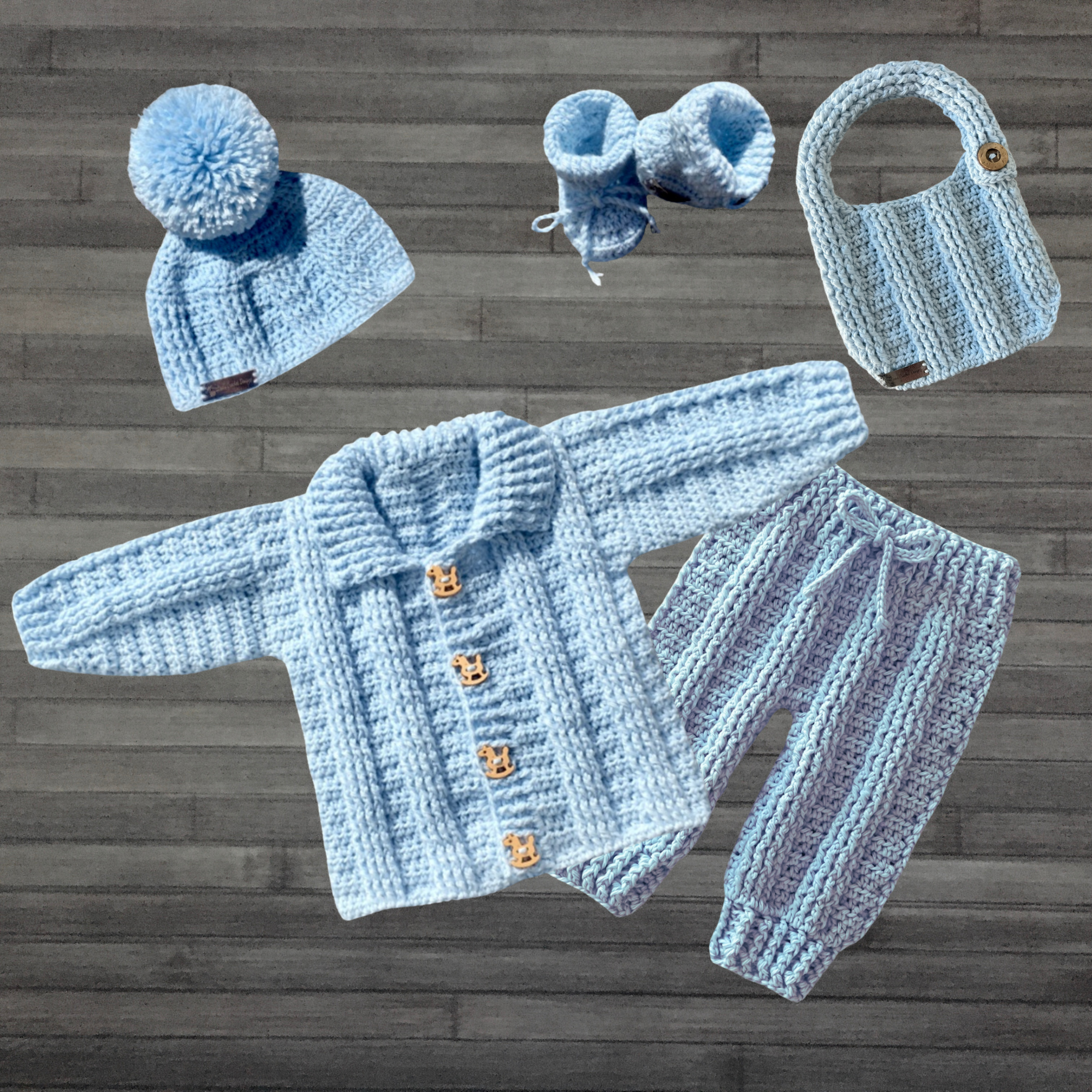 Zeb crochet cardigan, hat, booties, pants and bib flat lay on wood. Five-piece digital pattern PDF collection.